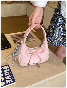 Detail van roze canvas hobo tas met strik, sterrenprint en zilveren hanger op houten tafel