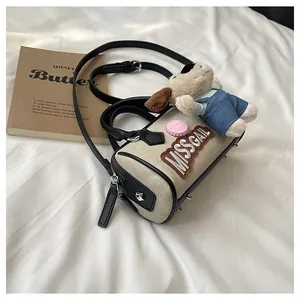 Close-up of beige canvas Boston bag with black leather trim and cute puppy plush charm