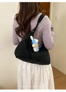 Détail du sac hobo en daim noir avec bandoulière tissée et breloque chiot faite à la main