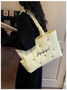 Detail of cream quilted tote bag featuring black bow accents and cloud-style handle