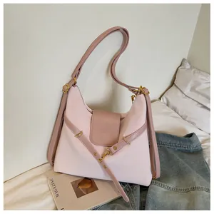 Detailopname van roze tweekleurige hobo-tas met goudkleurig metaal op wit beddengoed