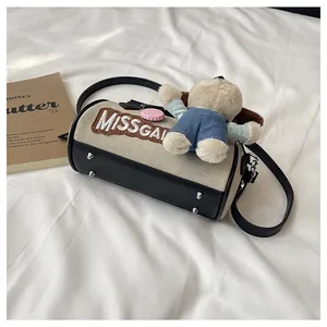 Detail of canvas Boston bag featuring MISSGAI embroidery and cute plush bear charm