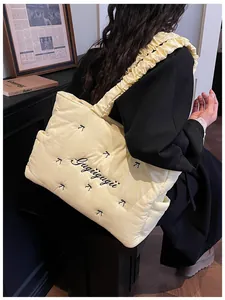 Detail of light yellow quilted tote with bow embroidery and ruffled shoulder strap