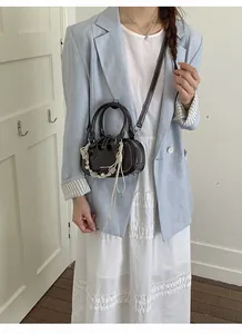 Chic dark brown mini crossbody bag with woven charm styled with a linen blazer suit