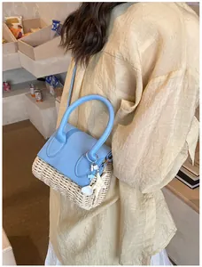 Close-up of mini straw bag with blue leather top and seashell charm accessory