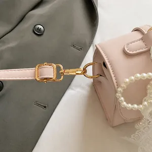 Detail view of pink mini square bag with golden hooks and elegant pearl chain handle