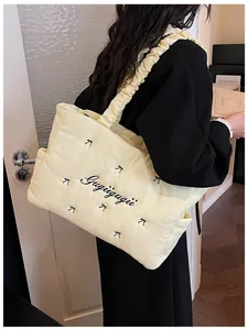 Detail view of light yellow quilted tote with bow embroidery and ruffled shoulder strap