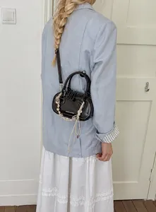 Rear view of a black Boston handbag styled with a light blue blazer and white dress