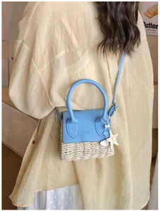 Detail of summer woven straw crossbody bag with blue leather flap and ocean charms