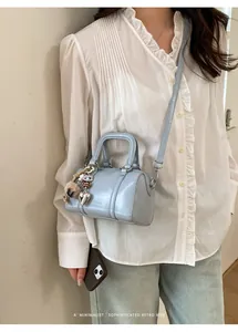 Detail of light blue mini Boston bag with heart charm and detachable strap