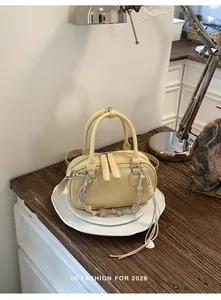 Detailed close-up of pale yellow Boston bag with woven beaded charm and textured PU leather
