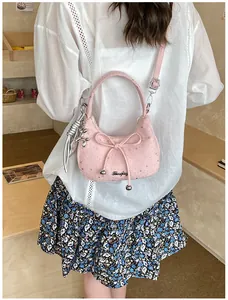 Roze crossbodytas met strik en zilveren sterren gedragen door model in een café