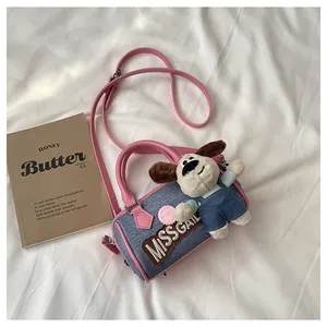 Detail of blue denim Boston bag with pink leather trim and a cute plush puppy charm