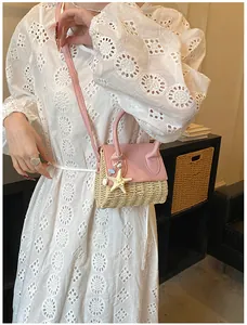 Detail of mini straw crossbody bag featuring pink leather trim and a starfish charm