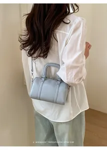 Minimalist light blue pillow bag with brand logo shown in a stylish back-view outfit
