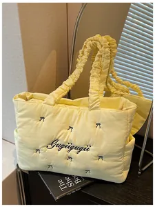 Close-up of quilted yellow tote bag featuring black bow embroidery and ruched handles