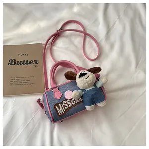 Detail of blue denim Boston bag featuring pink leather trim and a cute plush puppy charm