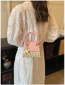 Detail of pink faux leather and straw mini crossbody bag with a starfish charm accent