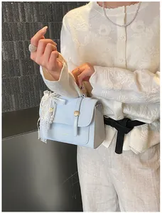 Detail of light blue leather handbag featuring lace trim and white pearl pendant charm