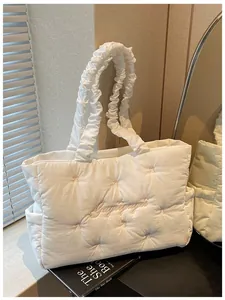 Detail of white quilted nylon tote bag with pink embroidery and ruffled shoulder strap