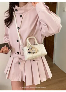 Detail of a creamy white Boston bag with silver hardware and a heart charm accessory