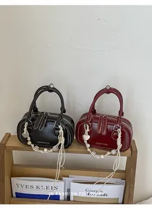 Detail of Boston bags featuring contrast stitching and bohemian charms on a wooden stand