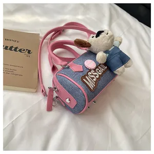 Detailed close-up of blue denim boston bag with pink leather trim and cute puppy charm