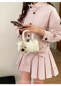 Detail of off-white leather Boston bag with heart charm and plush ball accessory