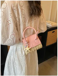 Pink leather and straw handbag with starfish charm shown on model in home setting