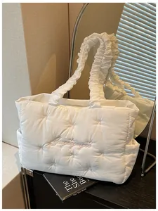 Detail of white quilted tote with pink bow accents and scrunchie shoulder strap