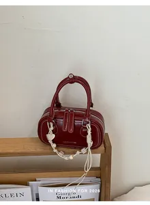 Detailed macro view of burgundy leather handbag with heart charm and beaded strap details