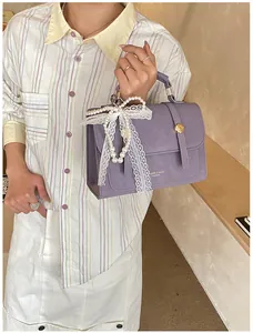 Detail of purple square handbag with pearl lace bow charm and gold ring closure