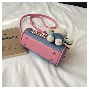 Detail of pink leather and denim Boston bag with plush bear charm and metal studs