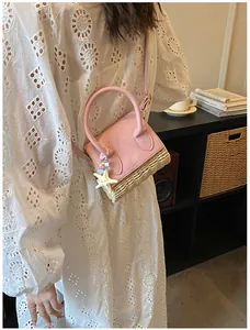 Mini pink leather and straw crossbody bag with starfish charm shown on white lace dress