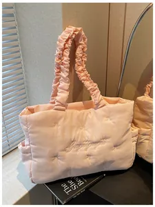 Detail of light pink quilted nylon tote with ruffled handles and bow embroidery