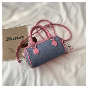 Detailed macro view of denim Boston bag with pink leather trim and a cute puppy plush charm