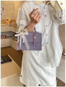 Detail of lavender small square bag with lace bow, pearl pendant and gold hardware lock