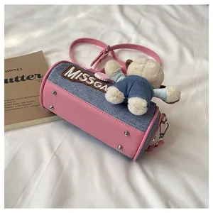 Detail of pink leather and denim Boston bag with plush bear charm and embroidery