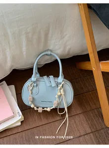 Detail of light blue PU leather handbag with zipper and woven beaded charm