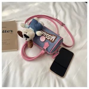 Detail of blue denim Boston bag with pink leather trim and cute puppy plush charm