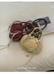 Detail of trendy shoulder bags in burgundy and beige with braided cord handles and charms
