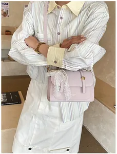 Detail of light purple leather square bag featuring lace bow and pearl charms