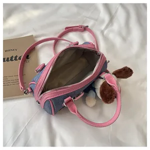 Detail of blue denim Boston bag with pink leather trim and a cute plush dog charm