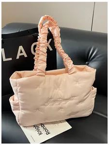 Detail of pink quilted tote with delicate bow embroidery and ruffled handles on a sofa