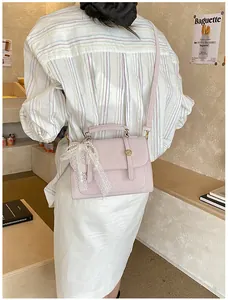 Detail of light pink faux leather bag with lace and pearl charm on an interior setting