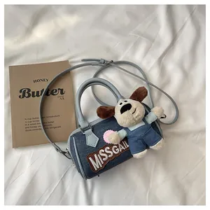 Detailed macro of blue denim Boston bag with embroidery and plush puppy charm