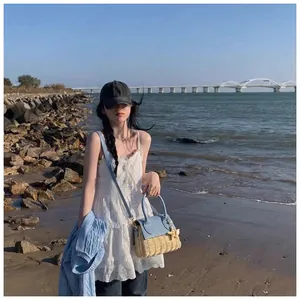 Close-up of summer straw crossbody bag with blue leather details on a beach background