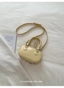 Detail of a creamy yellow mini crossbody bag with smooth texture and double zippers
