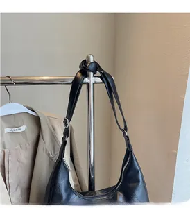 Detail of black leather crescent underarm bag with silver zipper and adjustable metal buckle