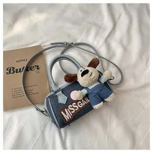 Detail of blue denim Boston bag featuring embroidered patches and a plush puppy doll